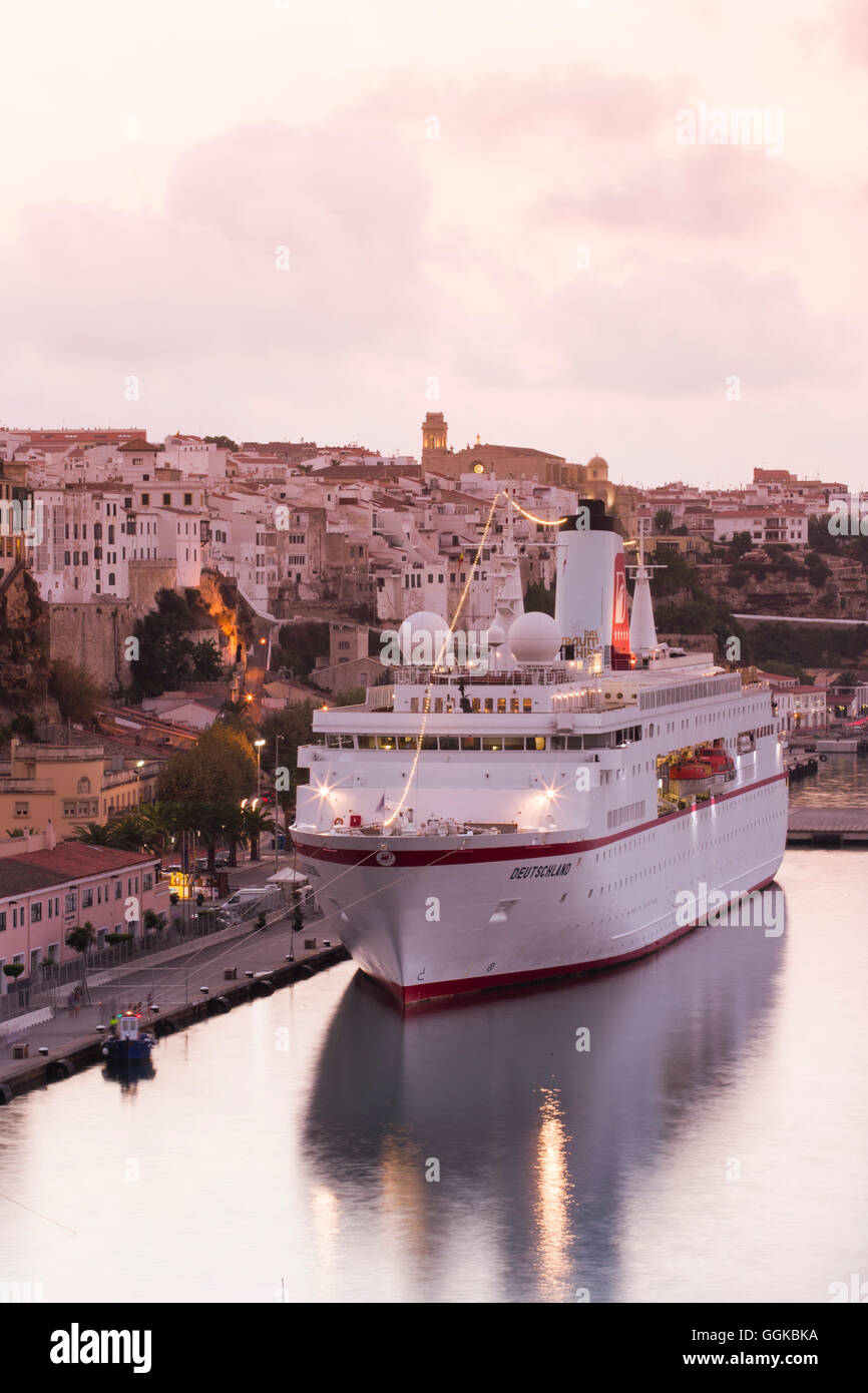 Barco Crucero MS Deutschland (Peter Deilmann Reederei) en el muelle y el casco antiguo de edificios al atardecer, Mahón, Menorca, Islas Baleares, Foto de stock