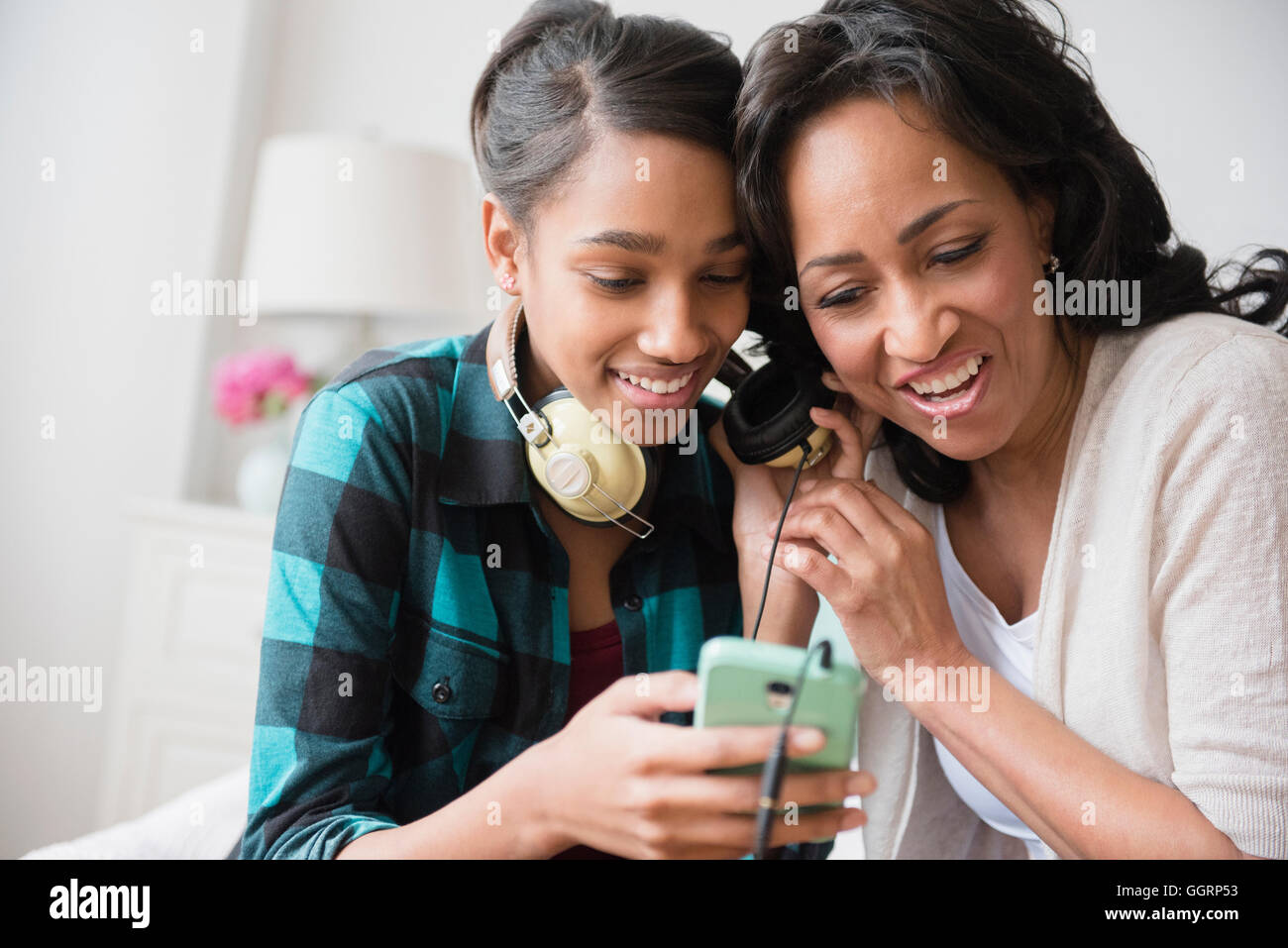 Madre e hija escuchando música en auriculares de teléfono celular Foto de stock