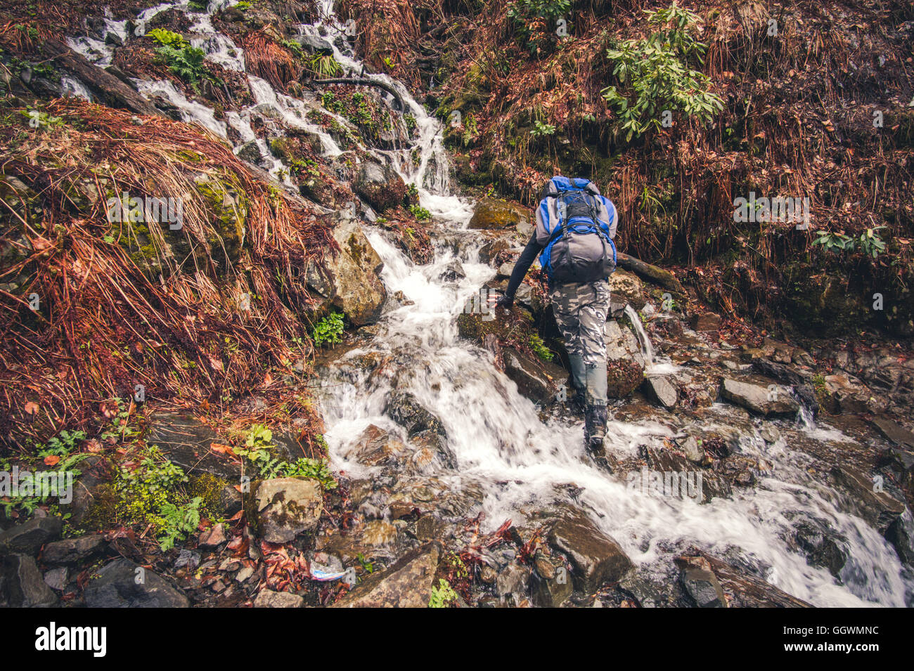 Hombre viajero con mochila cruzando montañas cascada en concepto de estilo de vida de Viajes Vacaciones de verano actividad extrema exterior s Foto de stock
