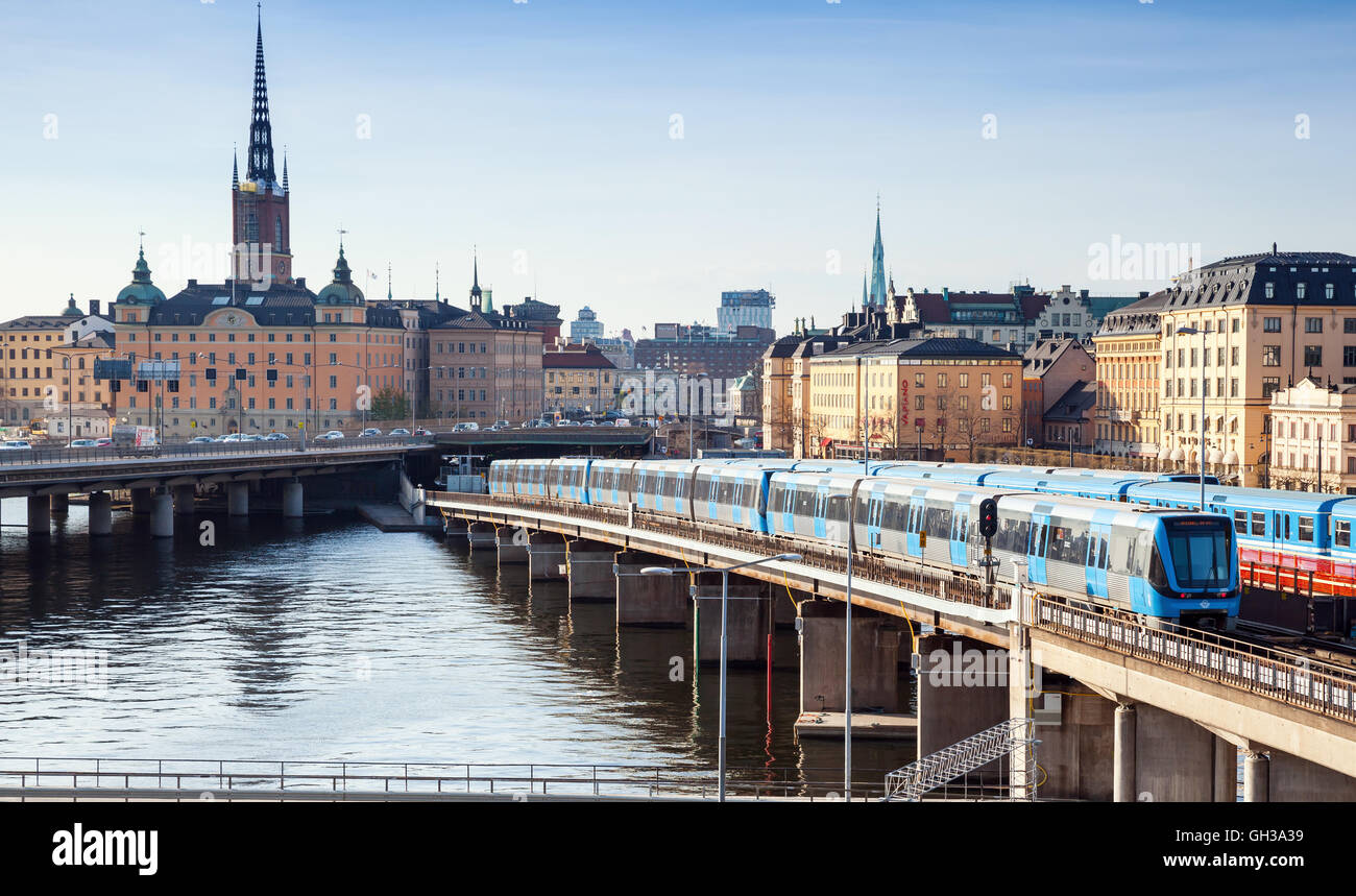 Estocolmo, Suecia - 3 de mayo de 2016: Ciudad de distrito de la ciudad de Gamla Stan en Estocolmo con tren azul va en el puente Foto de stock