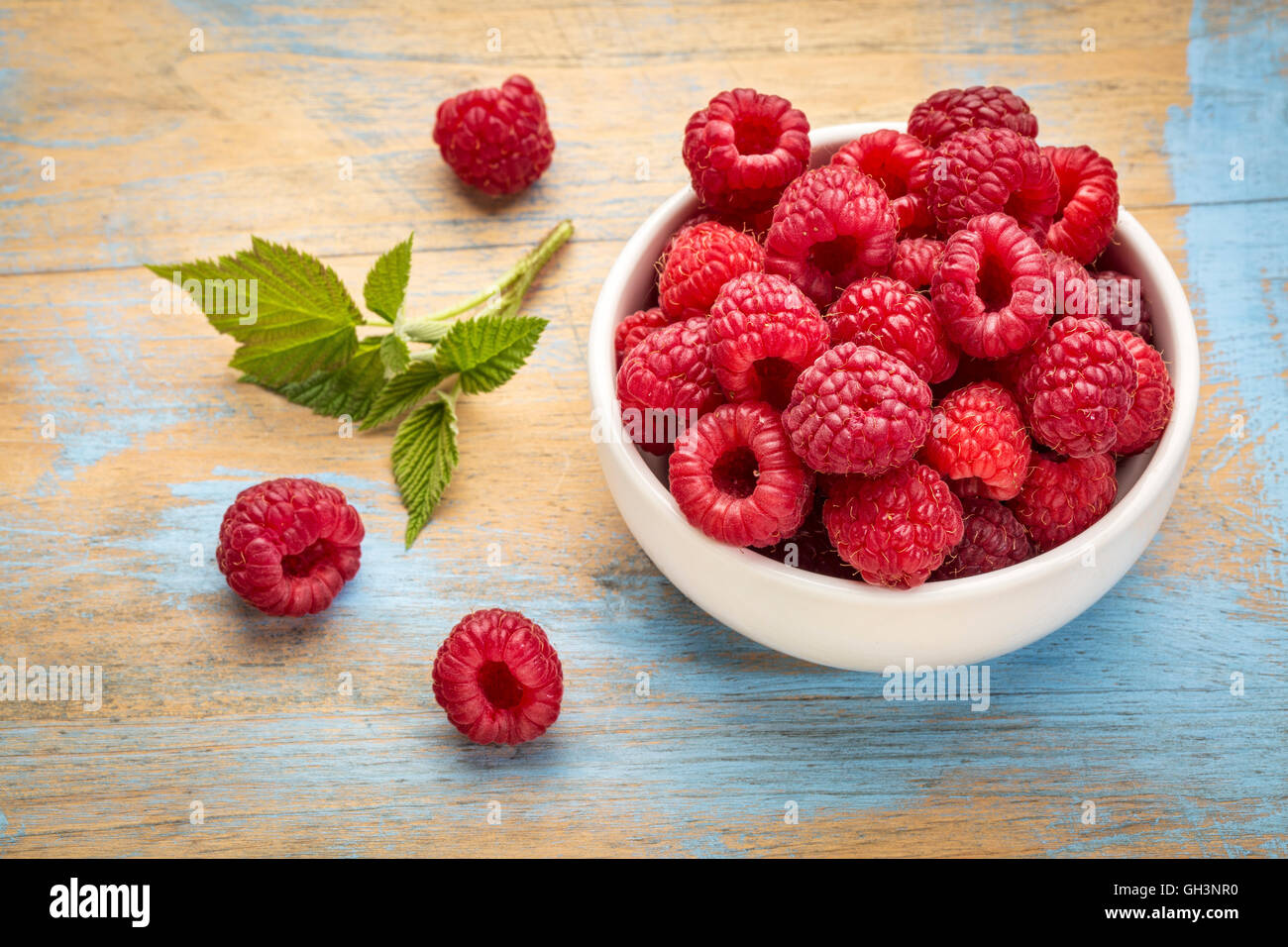 Un tazón de frambuesas rojas frescas en un jardín Foto de stock