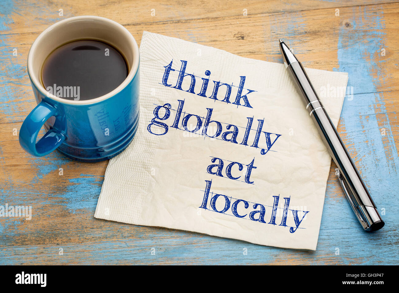 Pensar globalmente, actuar localmente - Recordatorio de la escritura a mano en una servilleta con una taza de café espresso Foto de stock