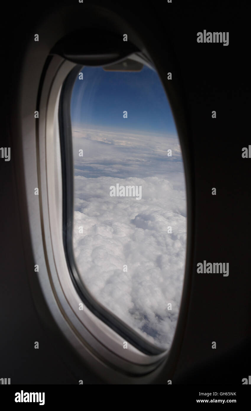 Vista sobre las nubes a través de la ventana de avión Foto de stock