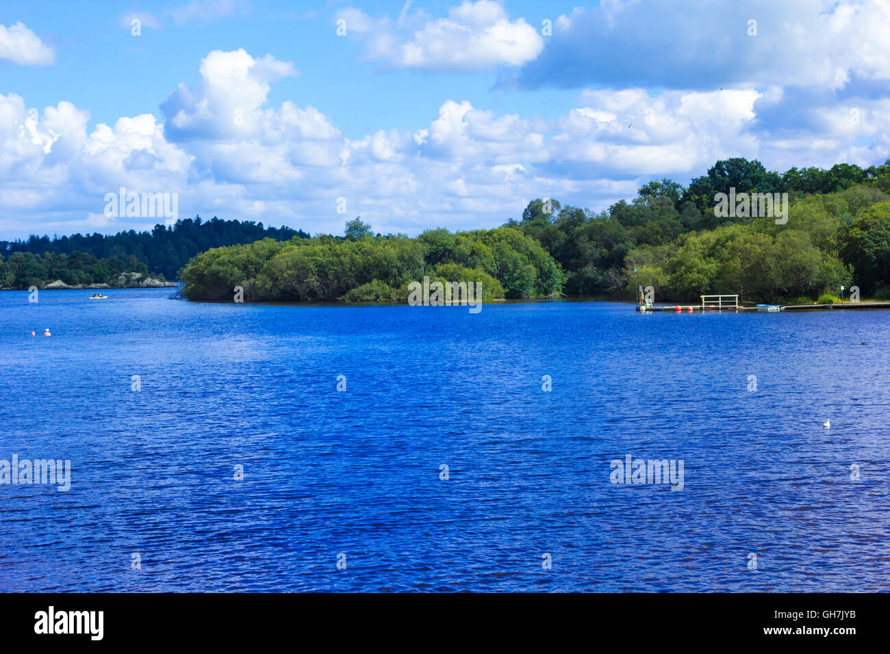 La gente remando en canoa a remo en calma azul lago Loch Lomond en Escocia Foto de stock