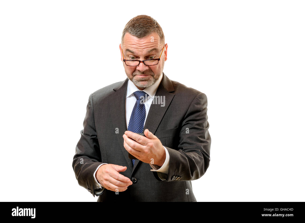 Empresario tirando rostro desdeñoso de disgusto como él lee un mensaje en su teléfono móvil celebrada en la longitud de los brazos, de la parte superior del cuerpo de Pentecostés Foto de stock