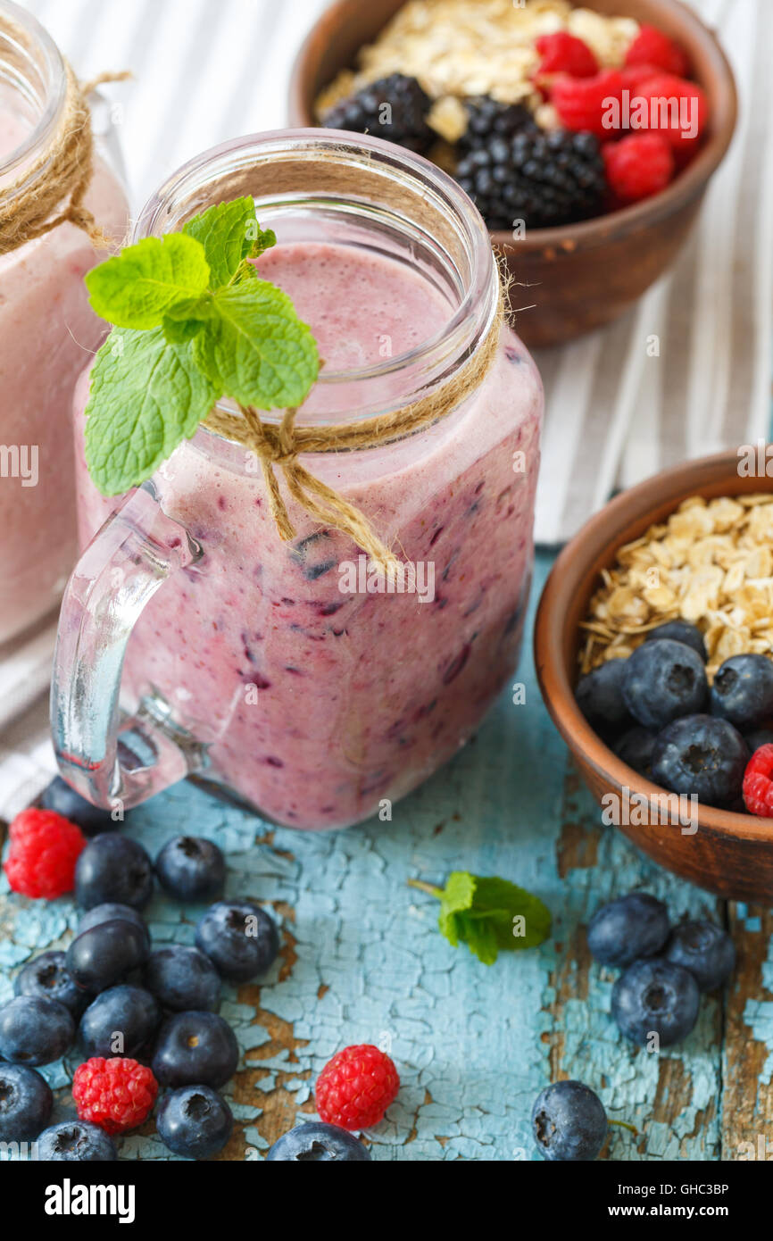 Bienestar y pérdida de peso concepto, Berry smoothie y avena sobre mesa de madera con ingredientes Foto de stock
