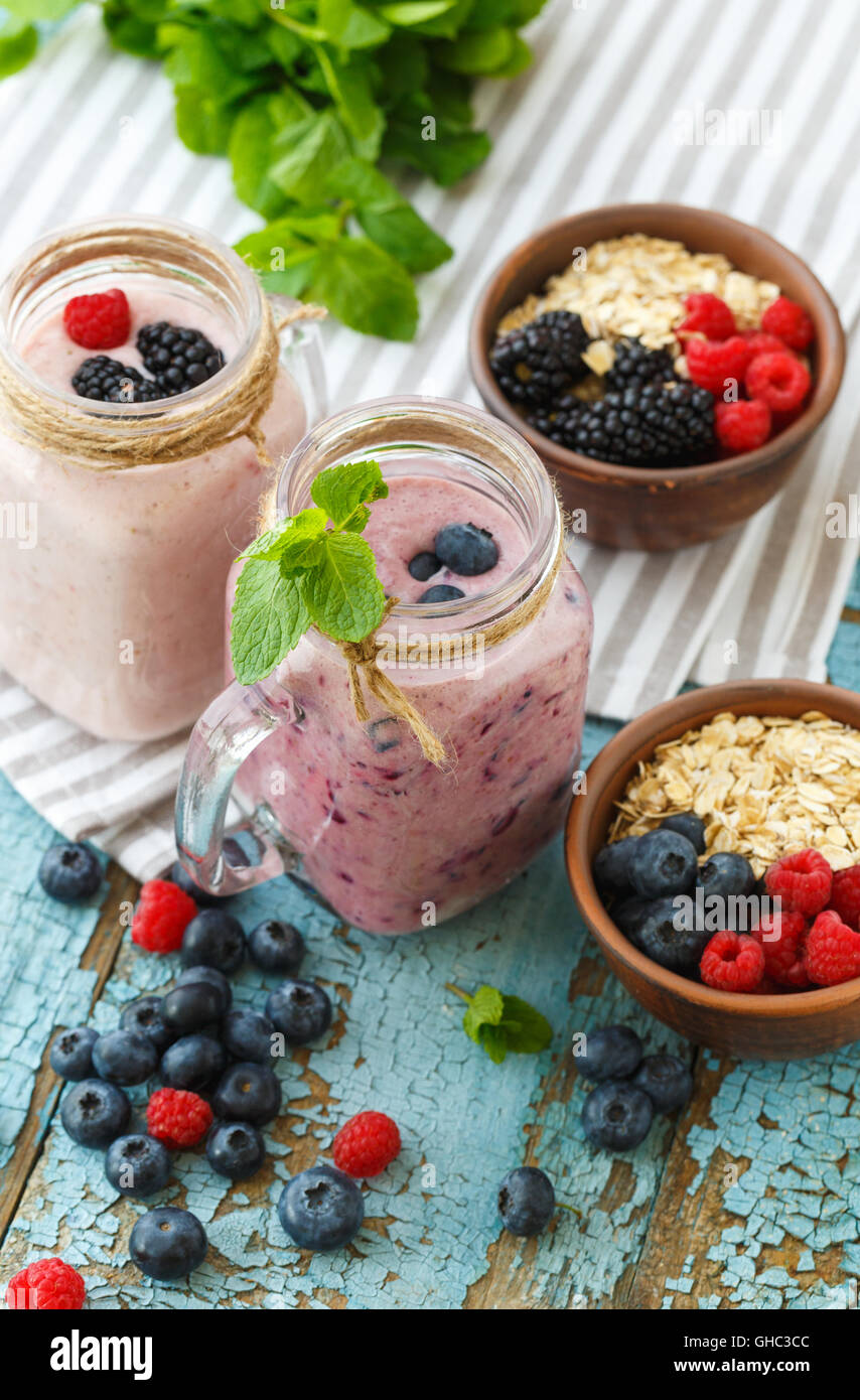 Bienestar y pérdida de peso concepto, Berry smoothie y avena sobre mesa de madera con ingredientes Foto de stock