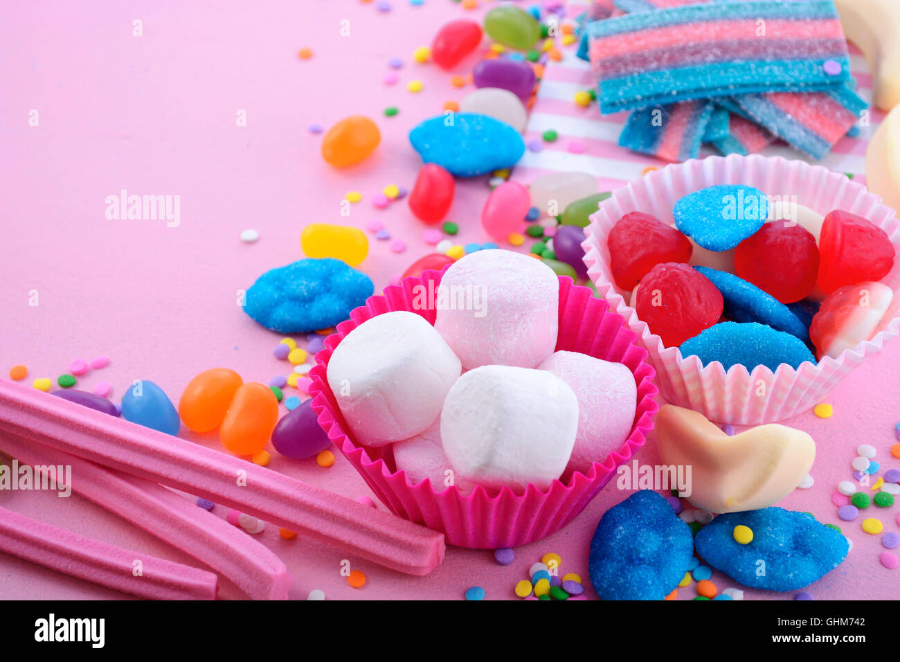 Caramelos de colores brillantes sobre fondo rosa mesa de madera para Halloween truco de tratar o cumpleaños infantiles cotillón, closeup. Foto de stock