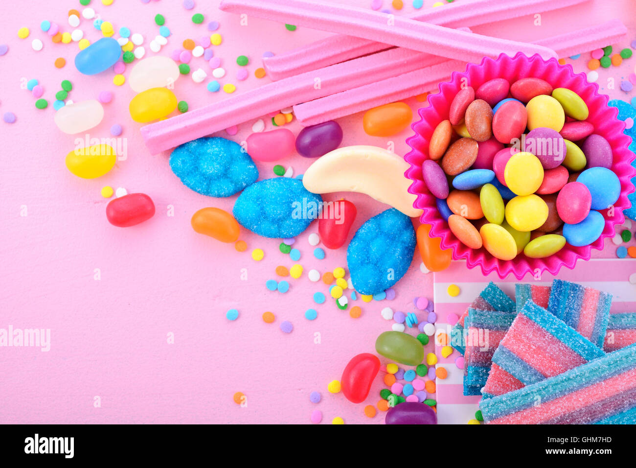 Caramelos de colores brillantes sobre fondo rosa mesa de madera para Halloween truco de tratar o cumpleaños infantiles cotillón, closeup. Foto de stock