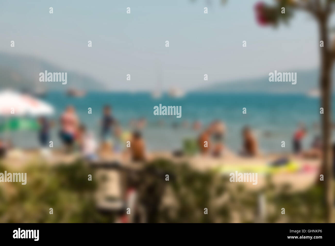 La gente borrosa en la playa con arena blanca y mar azul, un fondo del cielo Foto de stock