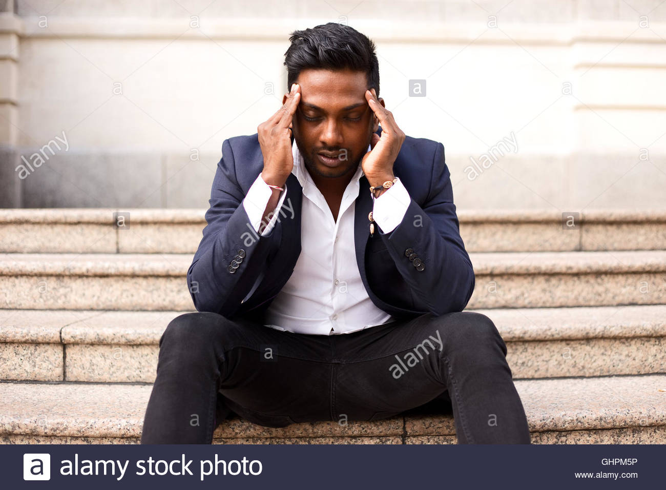 Hombre de negocios sentado en un paso con un dolor de cabeza Foto de stock