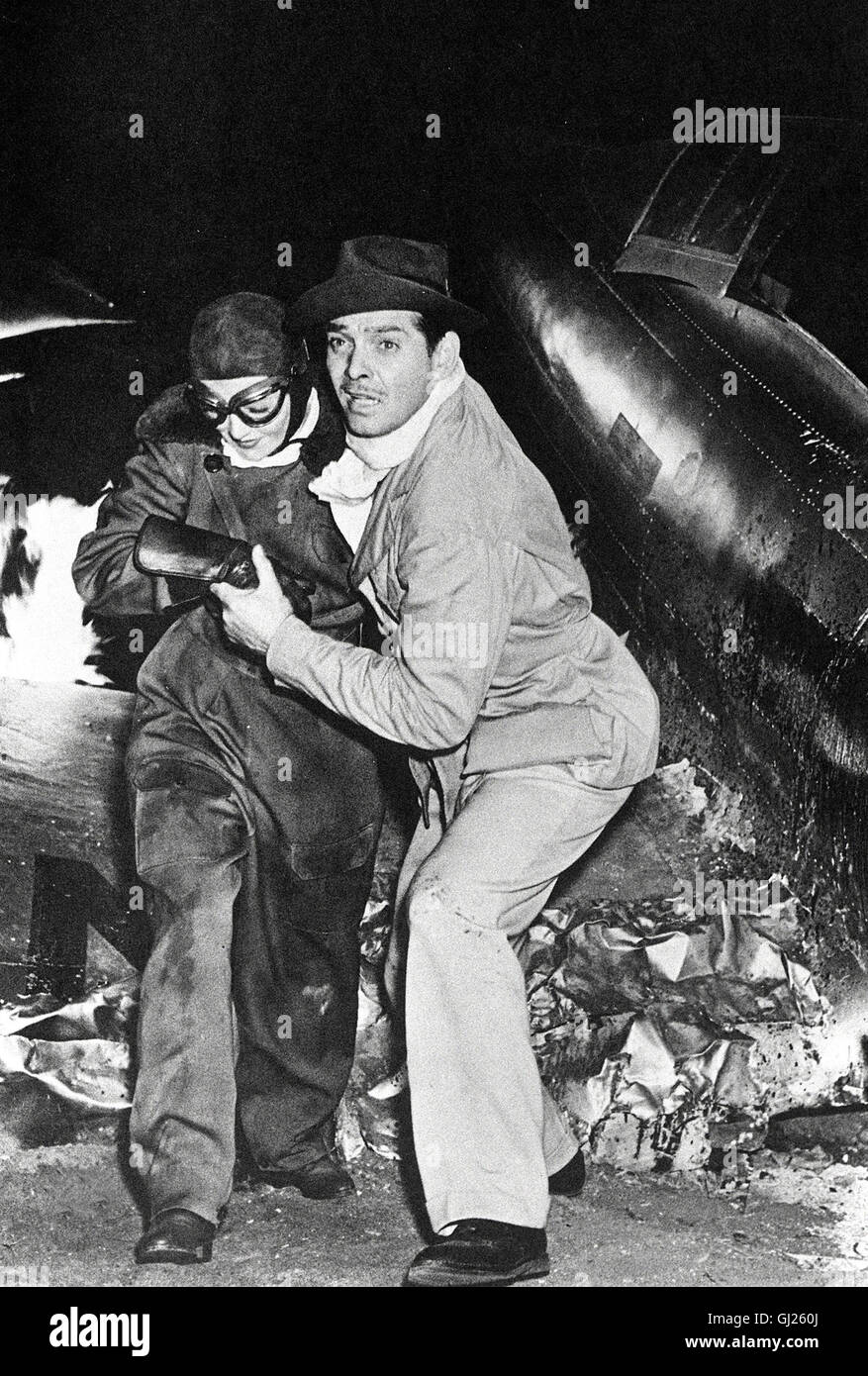 Chris Wochenschaureporter Hunter (Clark Gable) Rettet die attraktive Alma Harding (Myrna Loy) Aus den Trümmern brennenden eines Flugzeugs. aka. A caliente para manejar Foto de stock