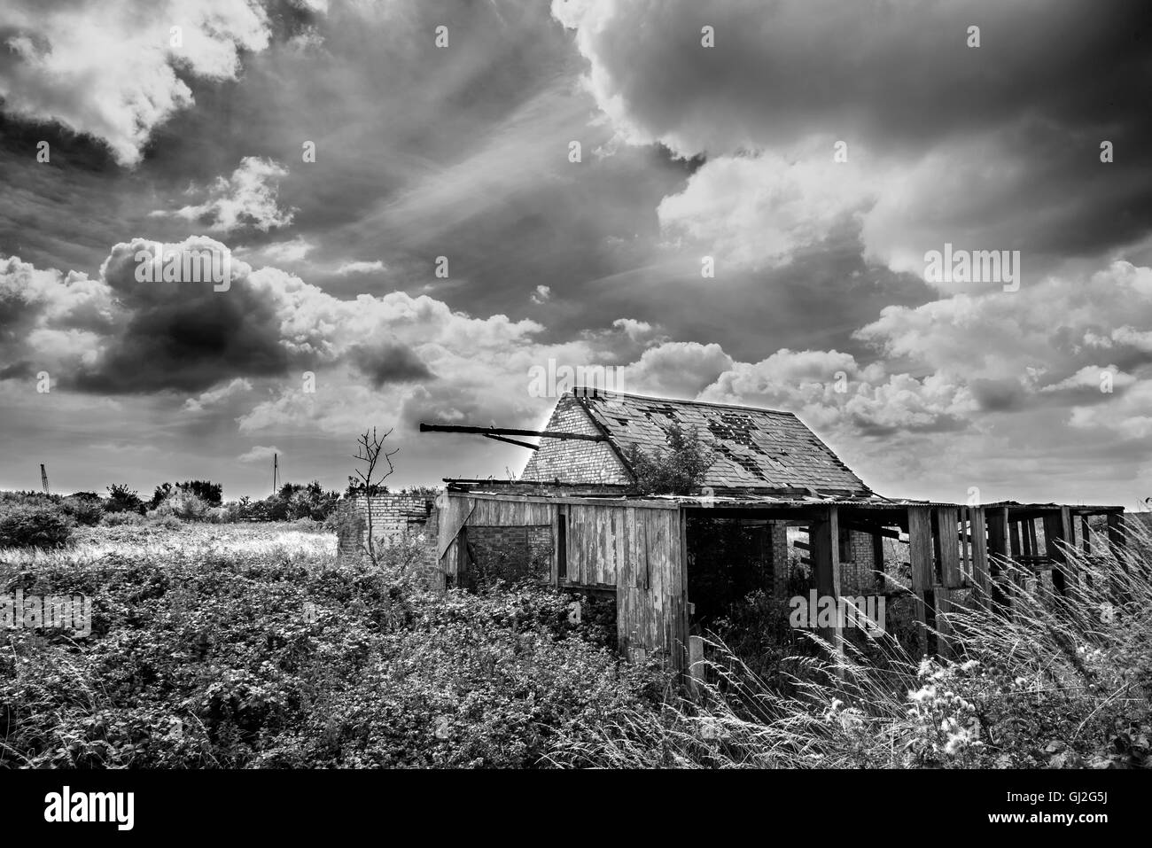 Fotografía en blanco y negro de una granja abandonada en el condado de Suffolk, con nubes hinchadas Foto de stock