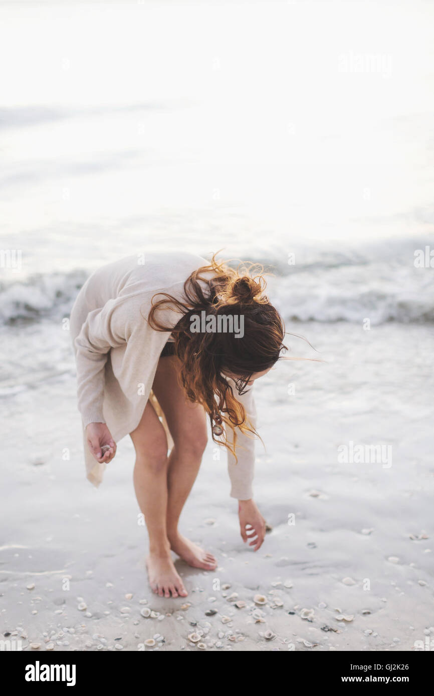 Mujer recogiendo conchas en la playa Foto de stock