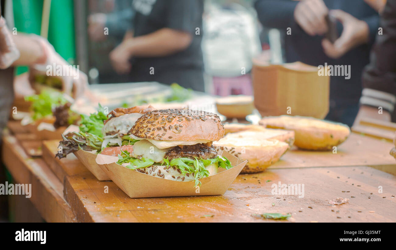 Una hamburguesa a la espera de ser terminado con la gente en el fondo Foto de stock