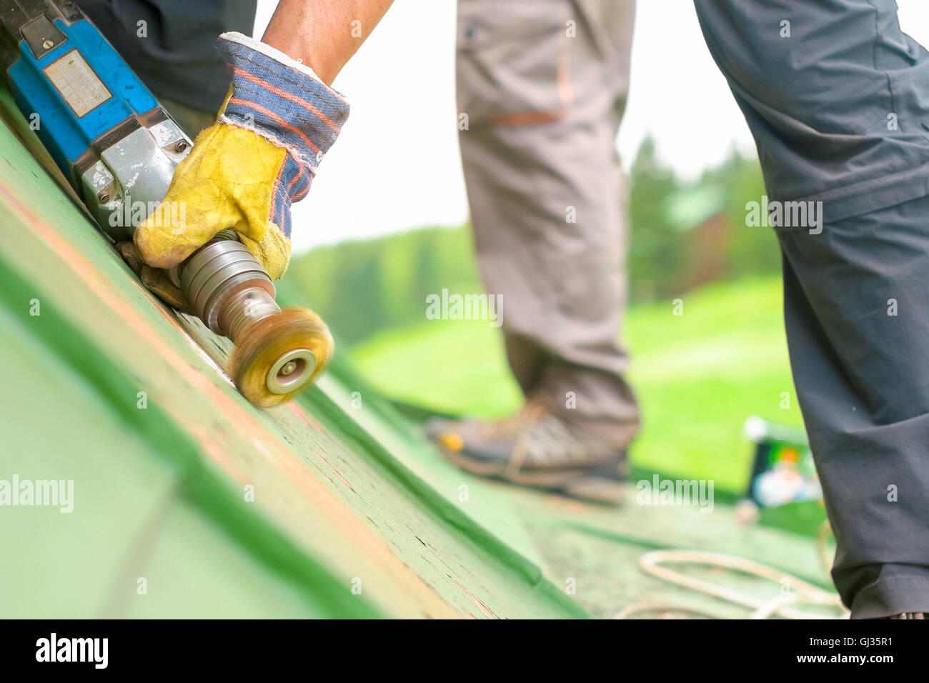 Trabajador de la construcción utilizando herramientas para raspar la  pintura verde en ángulo bajo Fotografía de stock - Alamy