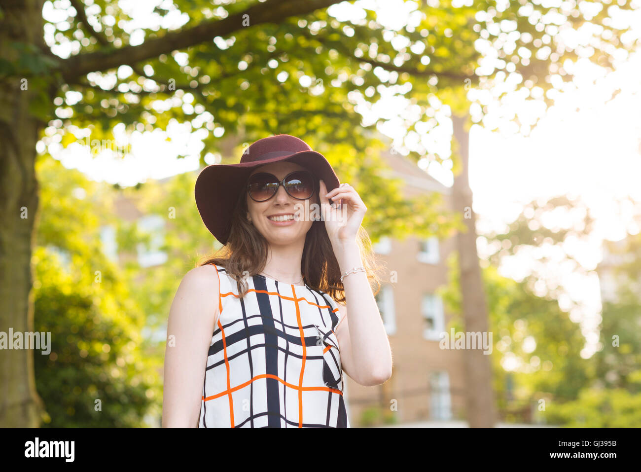 Mujer en la calle con gafas de sol y sombrero de disquete Foto de stock