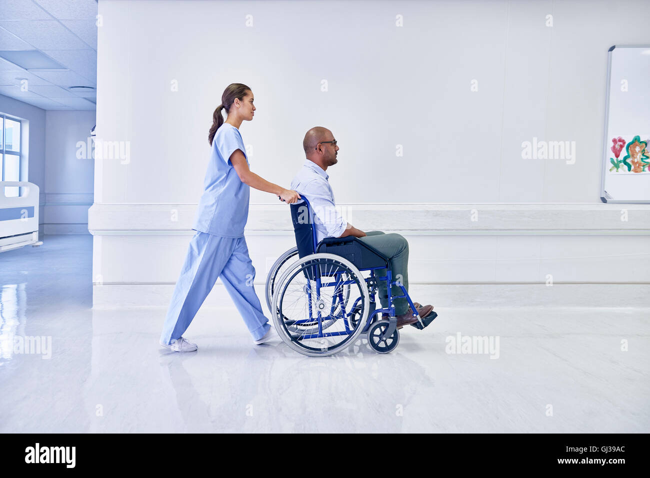 Doctor en el hospital empujando a pacientes en silla de ruedas Foto de stock
