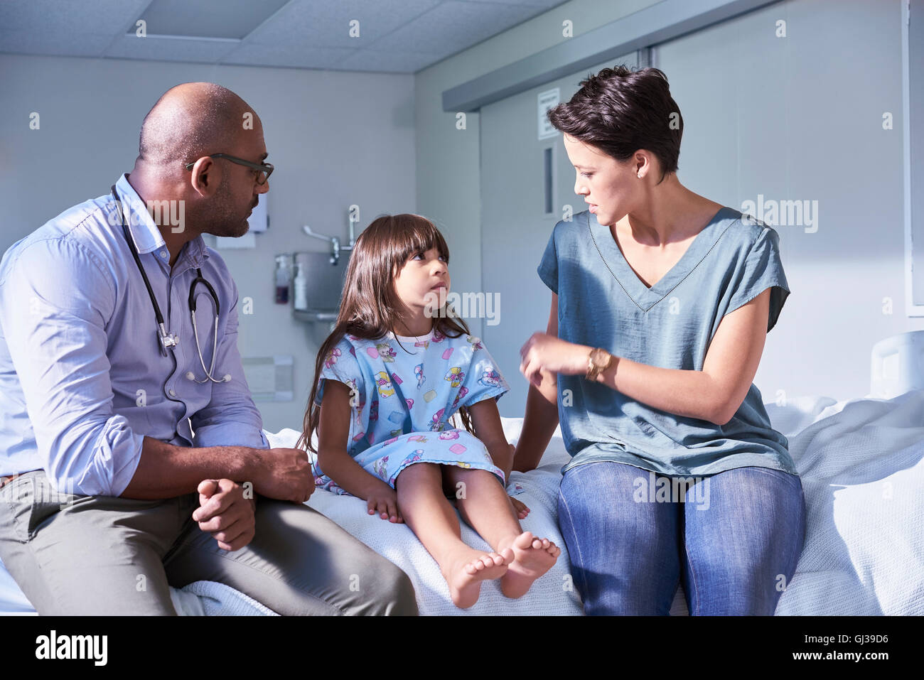 Médico varón explicando a la niña y a su madre del paciente en el hospital Children's ward Foto de stock
