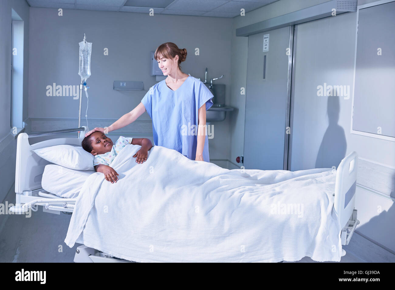 Enfermera tendiendo chica en la cama del paciente en el hospital Children's ward Foto de stock