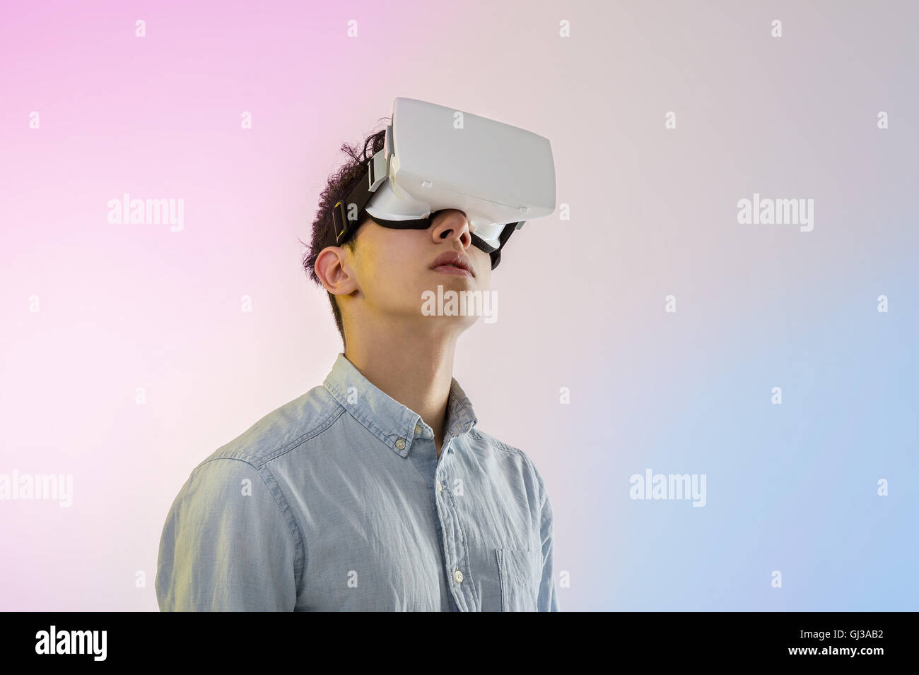 Joven hombre vestido con casco de realidad virtual, mirando hacia arriba Foto de stock