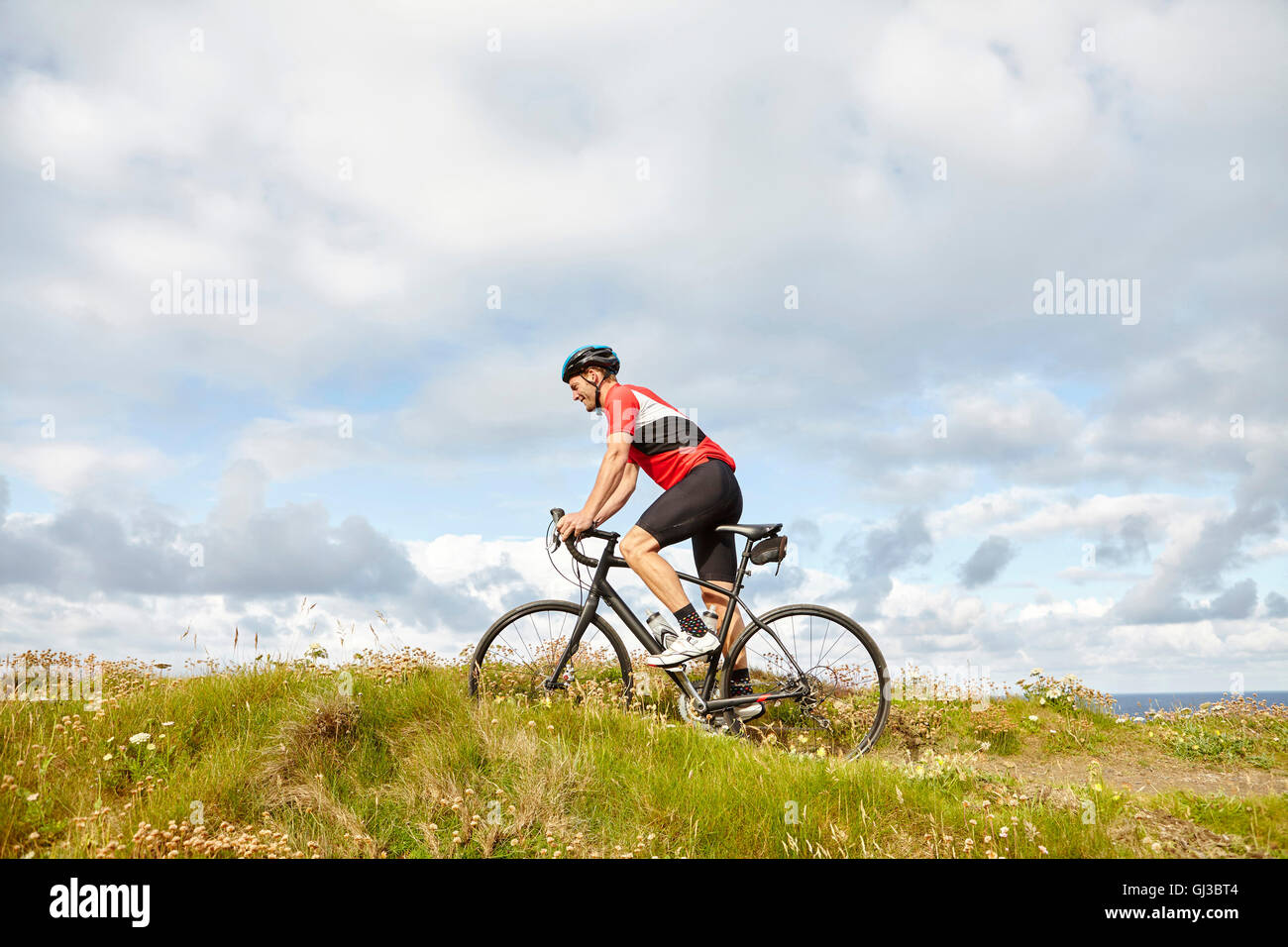 Equitación ciclista pasado meadow Foto de stock