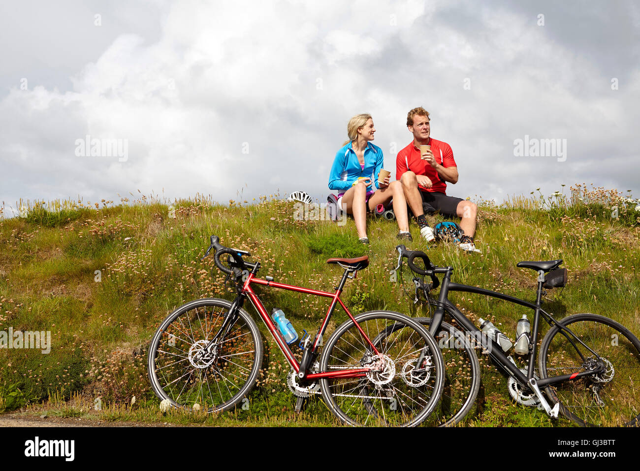 Los ciclistas relajarse y charlar en la cima de la colina de hierba Foto de stock