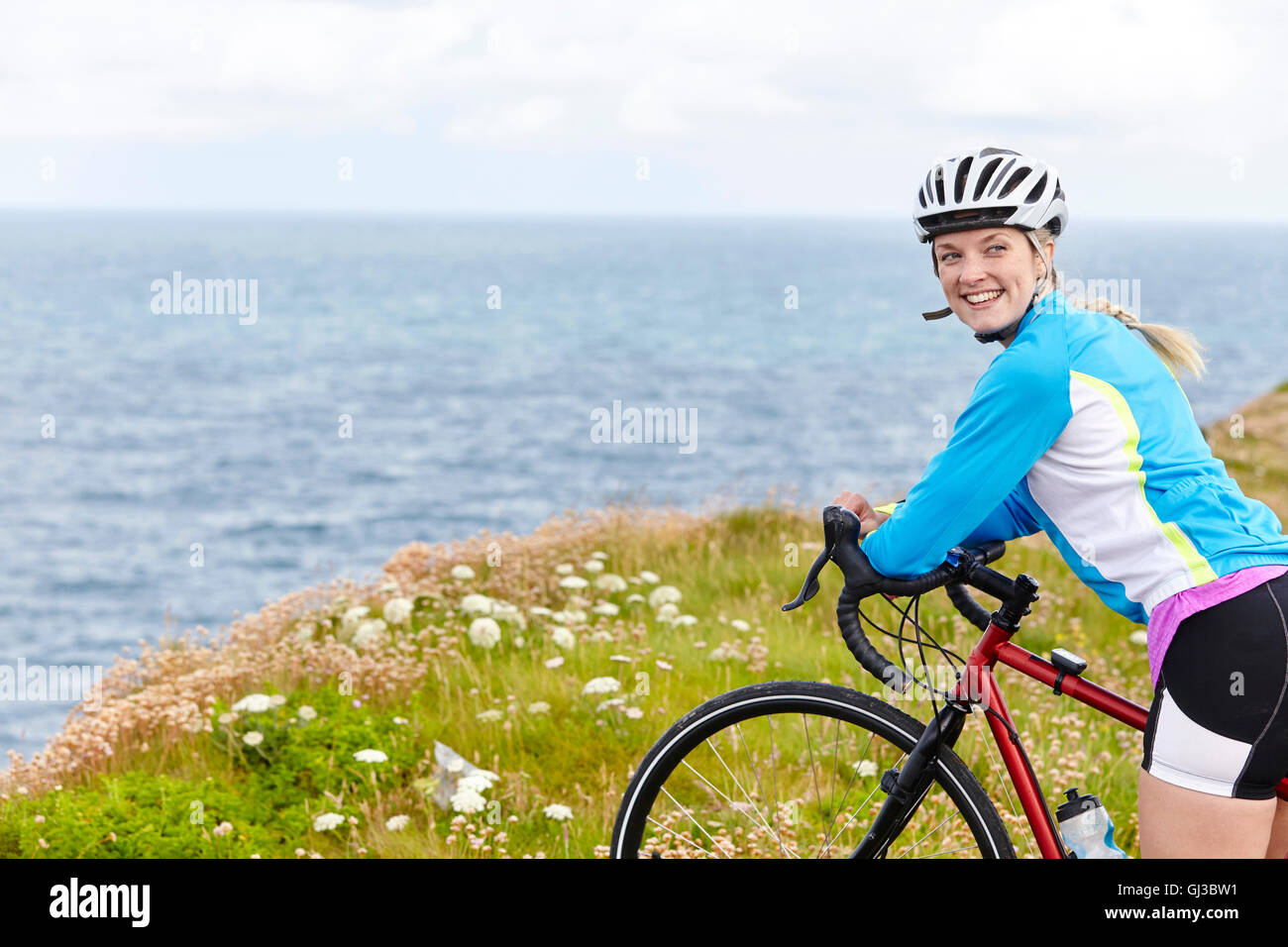 Ciclista parar en la colina con vistas al mar Foto de stock