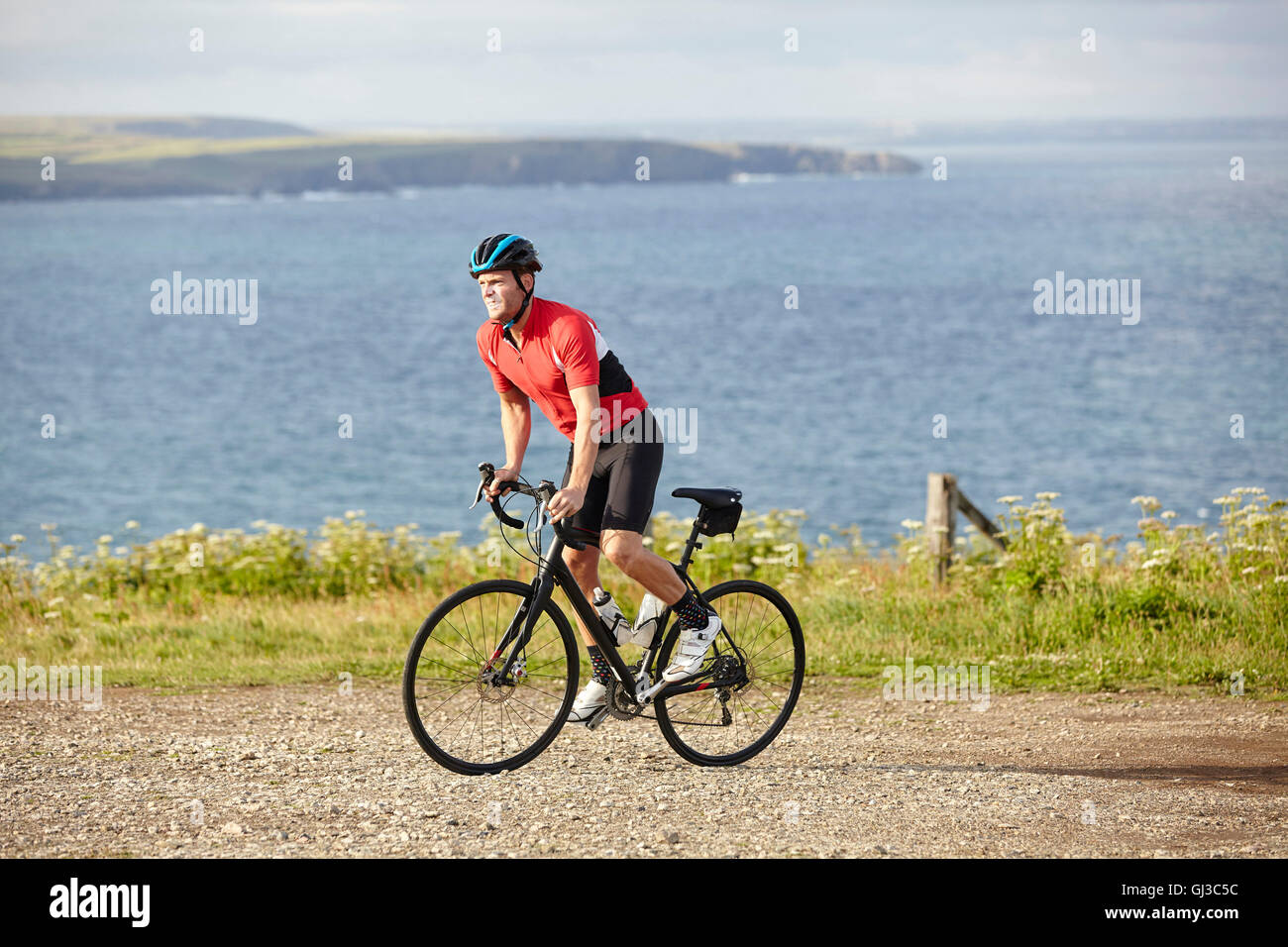 Ciclista cabalgando sobre ripio con vistas a Ocean Foto de stock