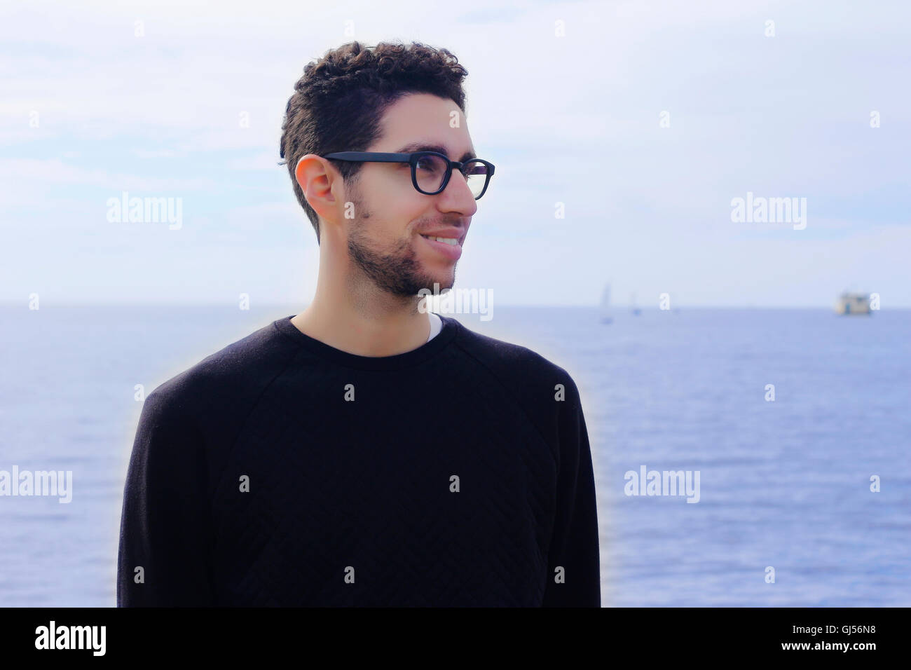 Retrato de joven hombre latino por el océano. Hispanic hombre sonriendo. Foto de stock