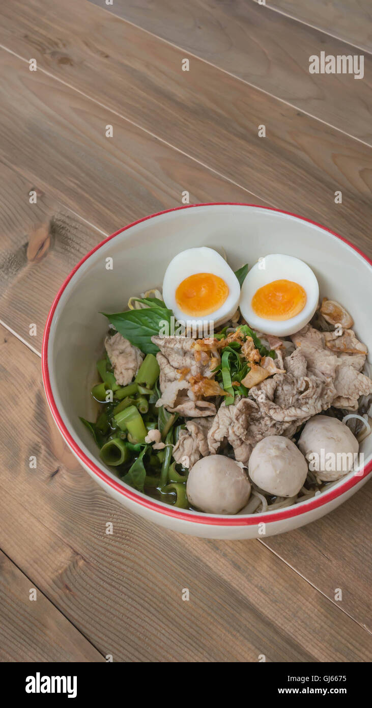 Blanco asiática fideos con carne de cerdo y verduras en un tazón sobre  fondo de madera Fotografía de stock - Alamy