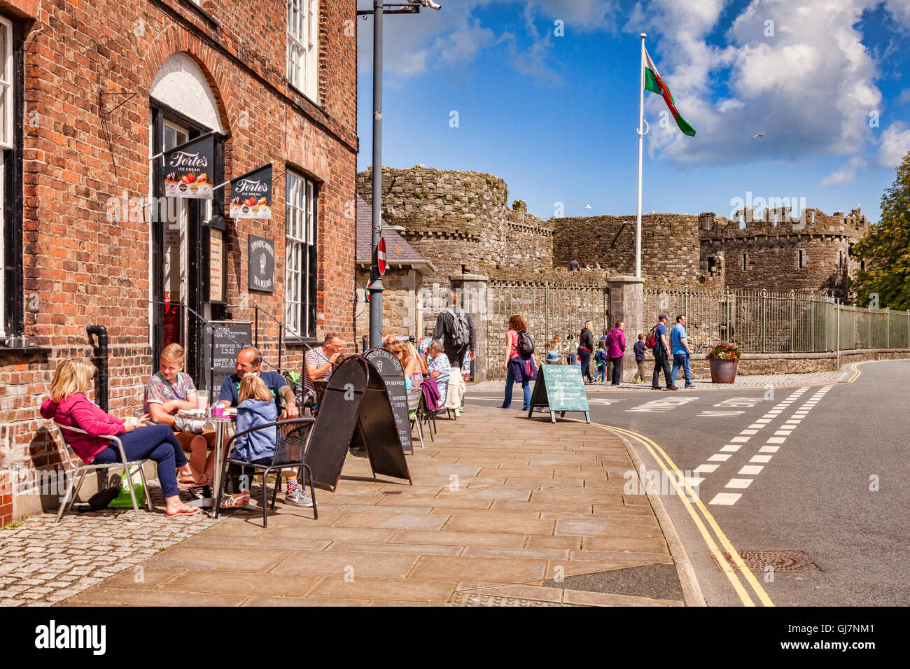 Los turistas en un pavimento cafe en Beaumaris, Anglesey, Gales, Reino Unido, con el castillo de fondo. Foto de stock
