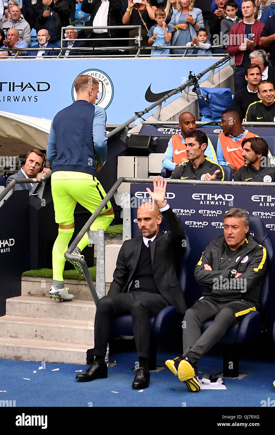 Manchester City Joe Hart (izquierda) toma su asiento en el banquillo detrás  el entrenador Pep Guardiola (centro) durante el partido de Liga Premier en  el Etihad Stadiium, Manchester Fotografía de stock -