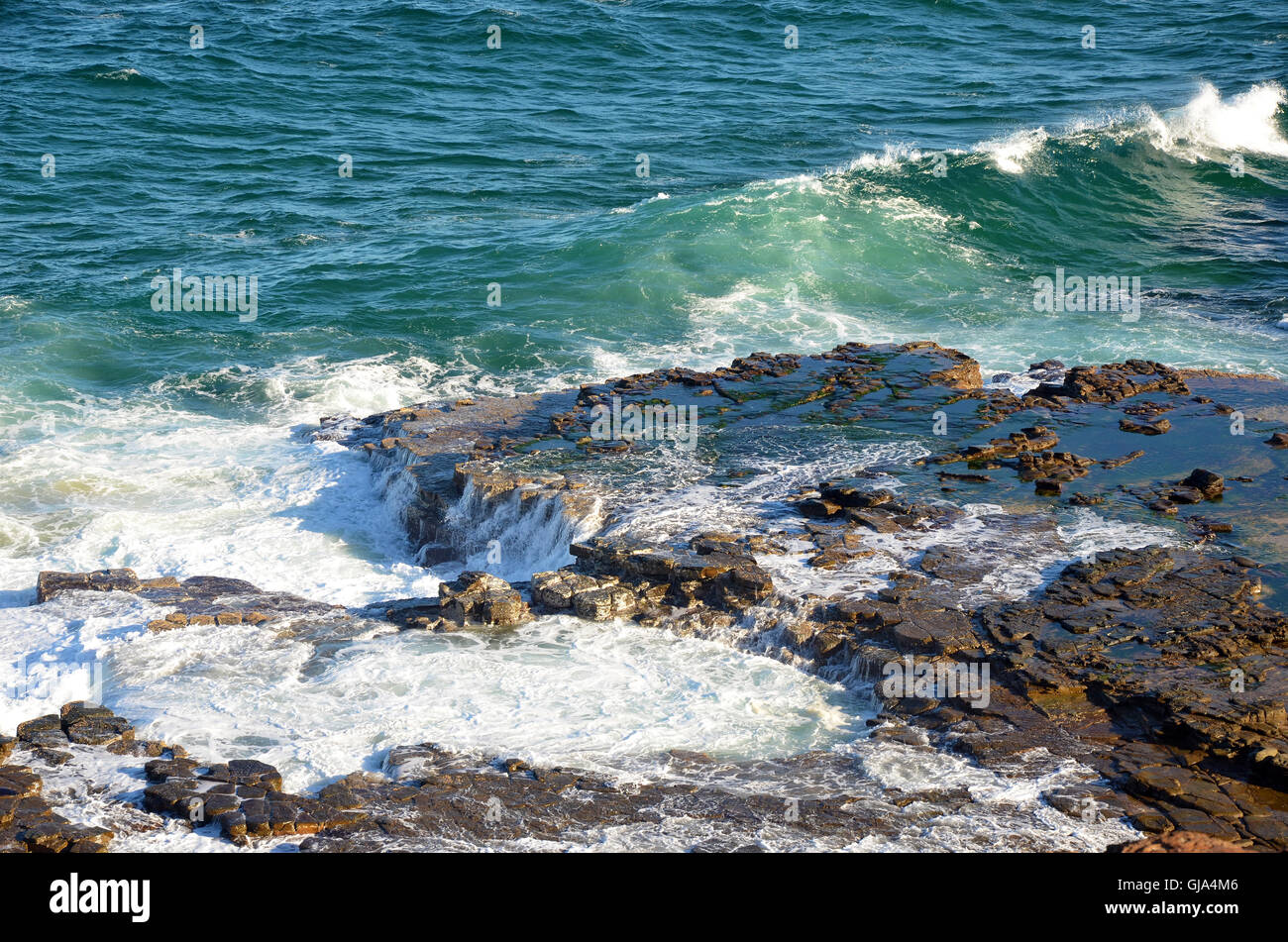 Agitadas olas sobre una plataforma de roca de mosaico erosionadas por las olas del mar en la costa de Nueva Gales del Sur, Australia Foto de stock