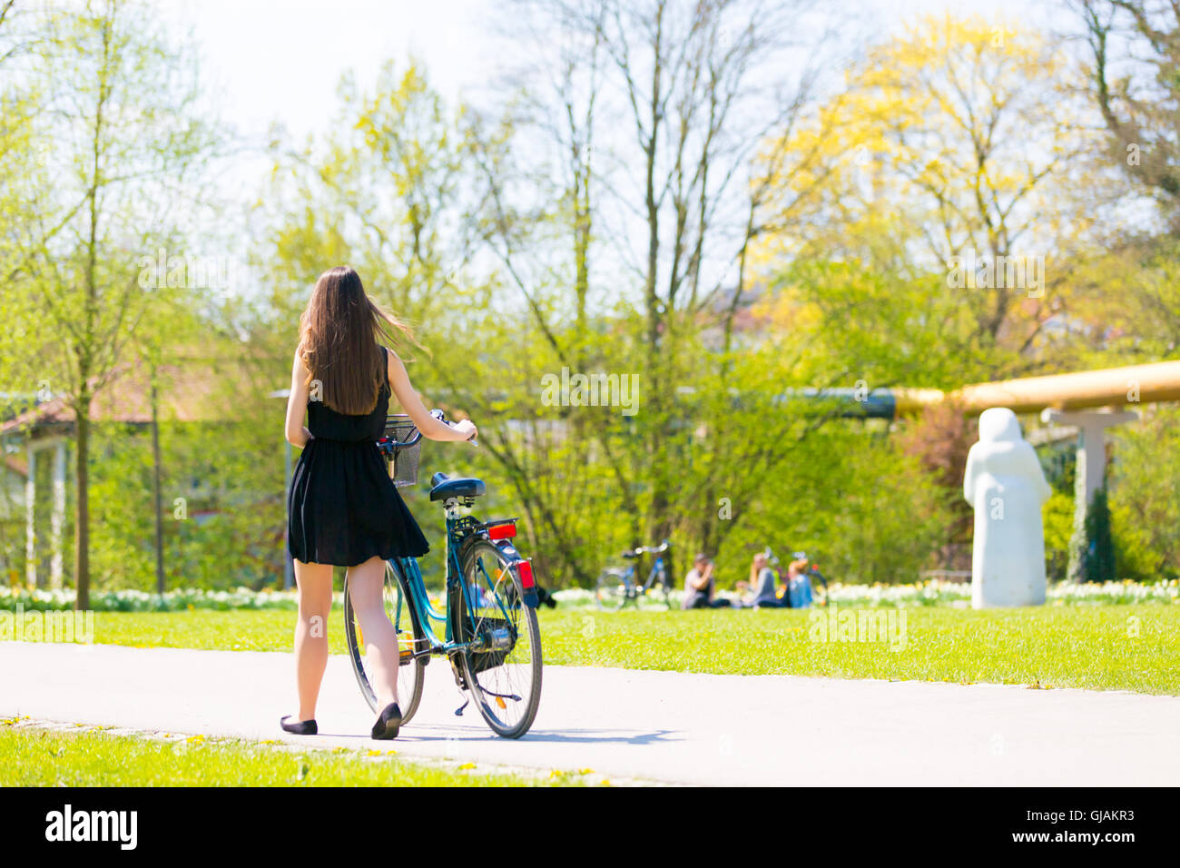 Mujer joven vistiendo negro vestido corto montando bicicleta Foto de stock