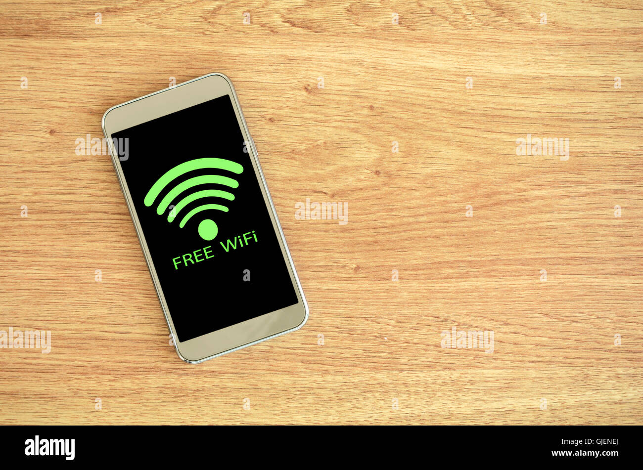 Wifi gratuita disponible. Teléfono inteligente sobre fondo de madera con Wifi gratuito firmar. Foto de stock
