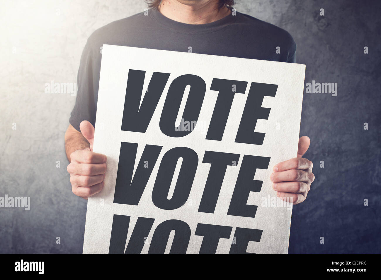 Hombre sujetando carteles con etiqueta votar, expresar actitudes y opiniones sobre las elecciones políticas Foto de stock
