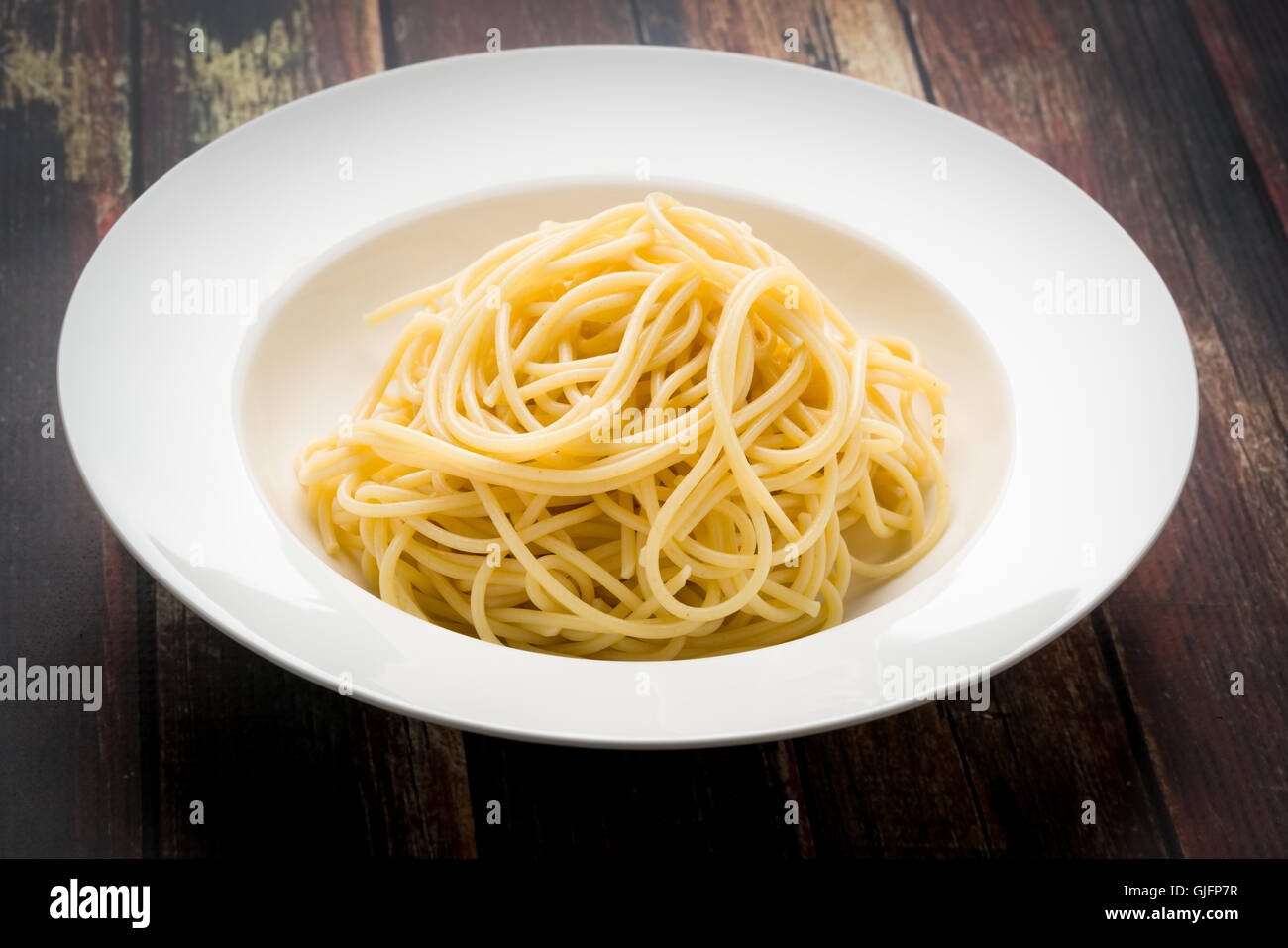 Los espaguetis en un recipiente blanco sobre una superficie de madera Foto de stock
