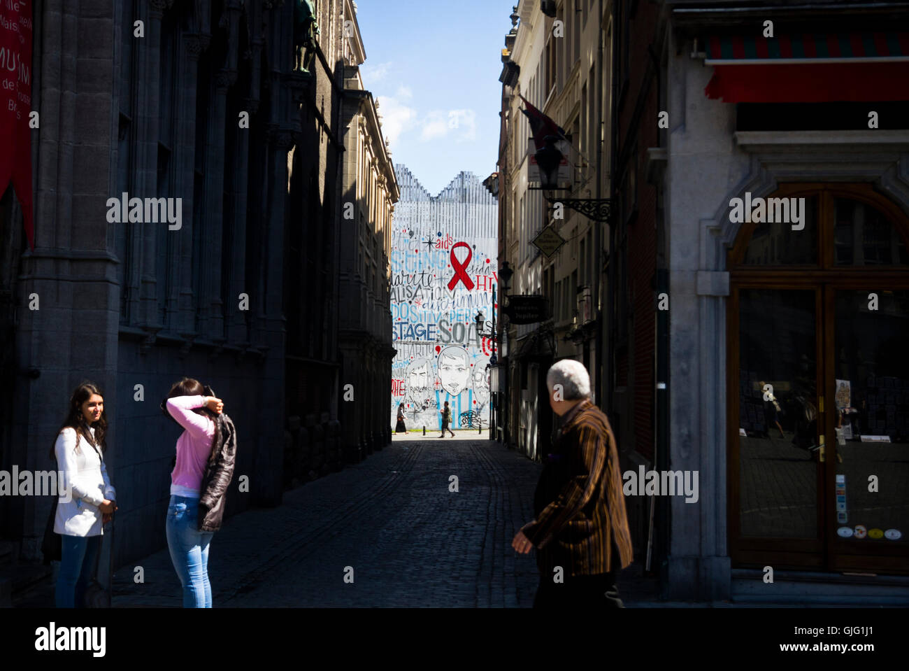 Los peatones atravesar una pared graffitied en Bruselas, Bélgica Foto de stock