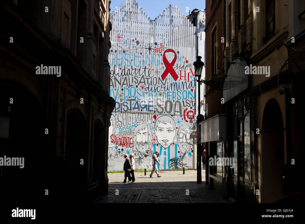 Los peatones atravesar una pared graffitied en Bruselas, Bélgica Foto de stock