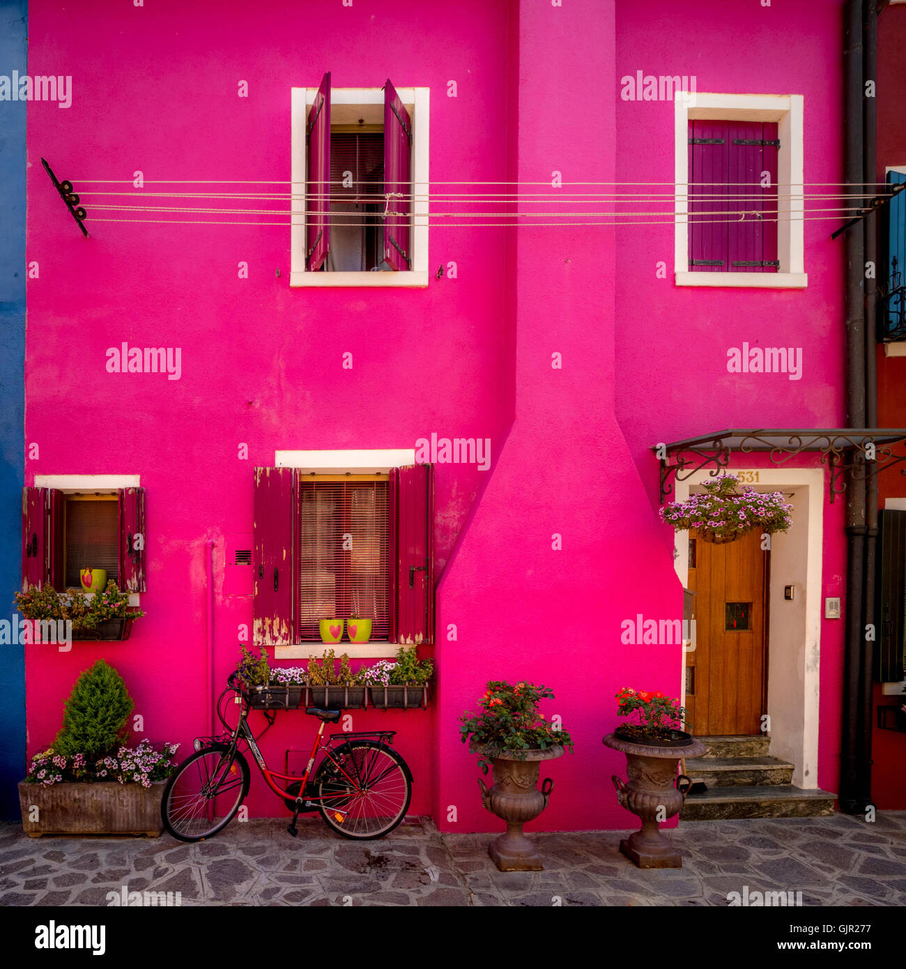 Casa rosa brillante con una bicicleta aparcada fuera, en la isla de Burano. Venecia, Italia. Foto de stock