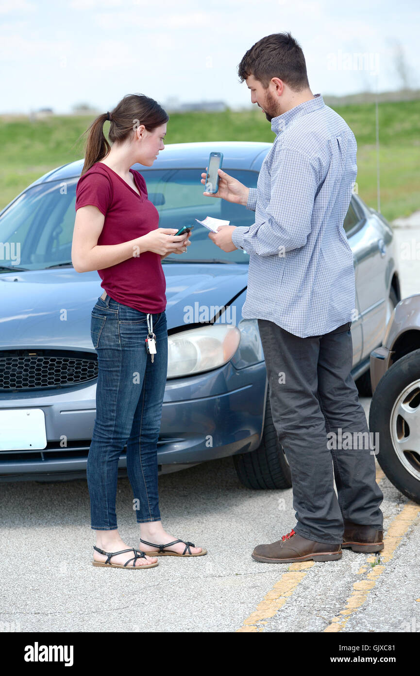 La mujer y el hombre joven intercambiar tarjetas de seguros después de accidente Foto de stock