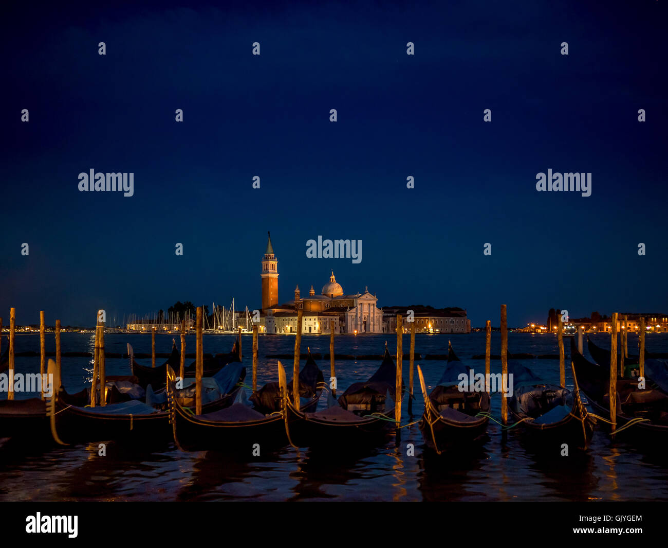 Las góndolas amarradas en la cuenca de San Marcos con San Giorgio Maggiore, en el fondo, por la noche. Venecia, Italia. Foto de stock