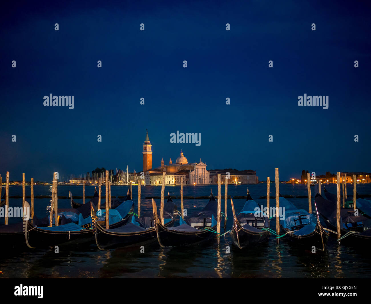Las góndolas amarradas en la cuenca de San Marcos con San Giorgio Maggiore, en el fondo, por la noche. Venecia, Italia. Foto de stock