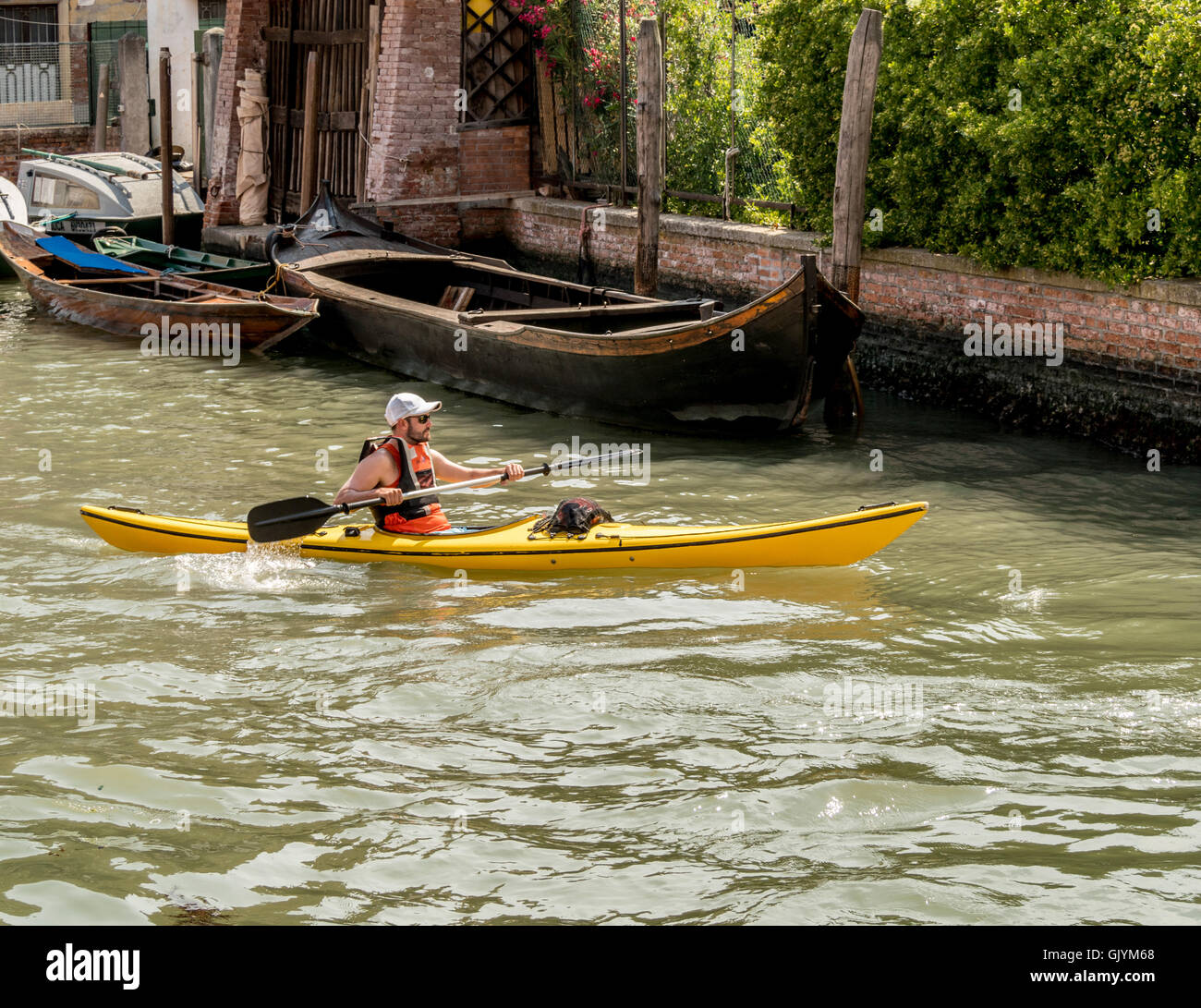 Kayakista macho amarillo en kayak, en un canal de Venecia, Italia. Foto de stock