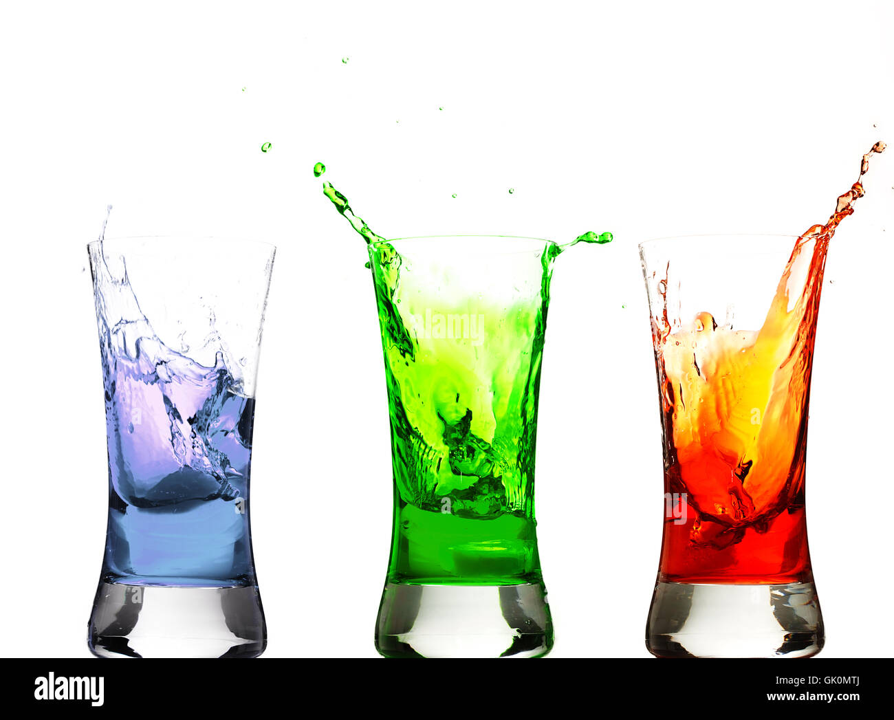 Cubo de hielo cayendo en coloridos vasos Foto de stock