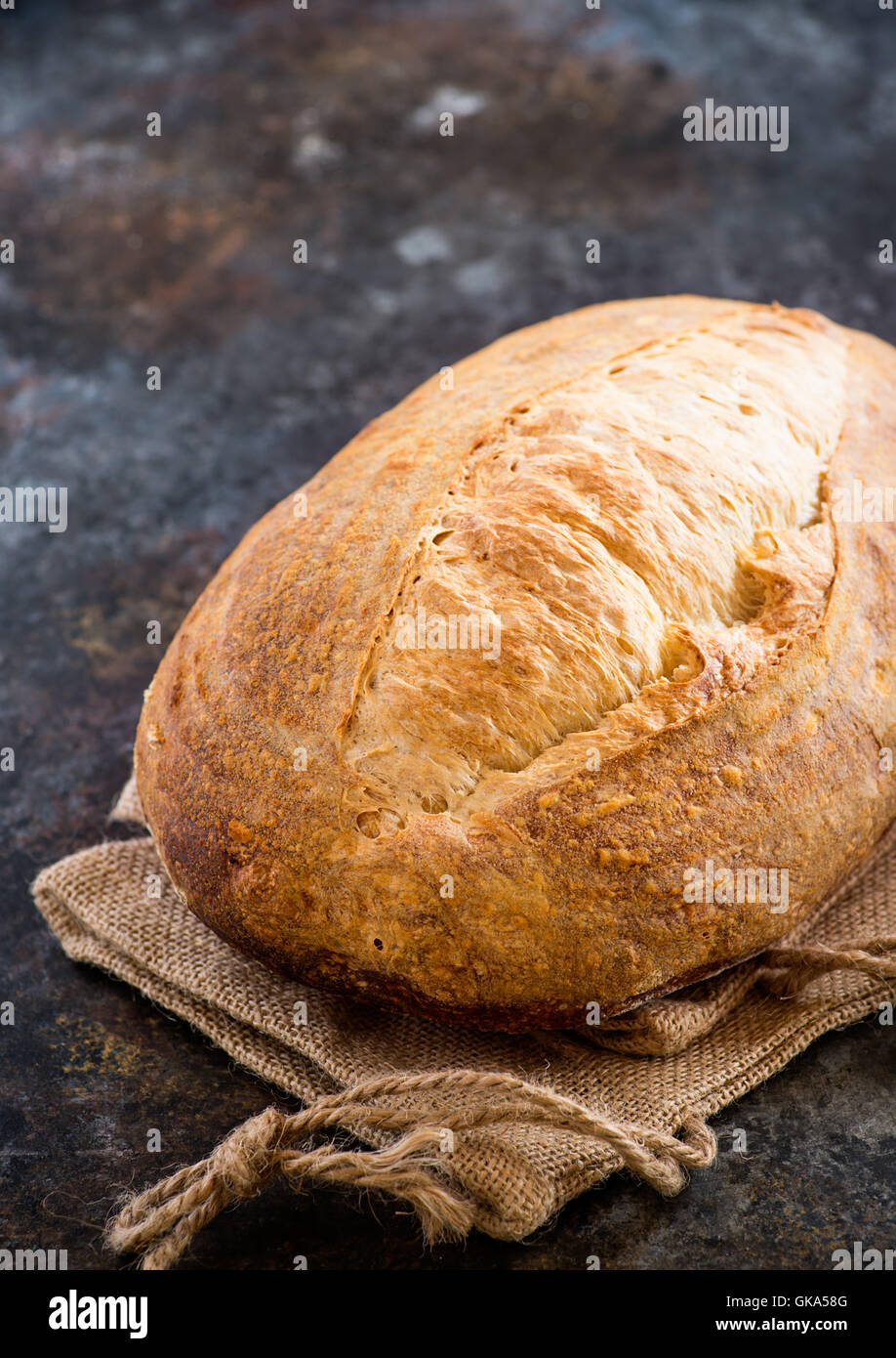 Casero hogaza de pan de masa fermentada sobre fondo oscuro, el enfoque selectivo Foto de stock