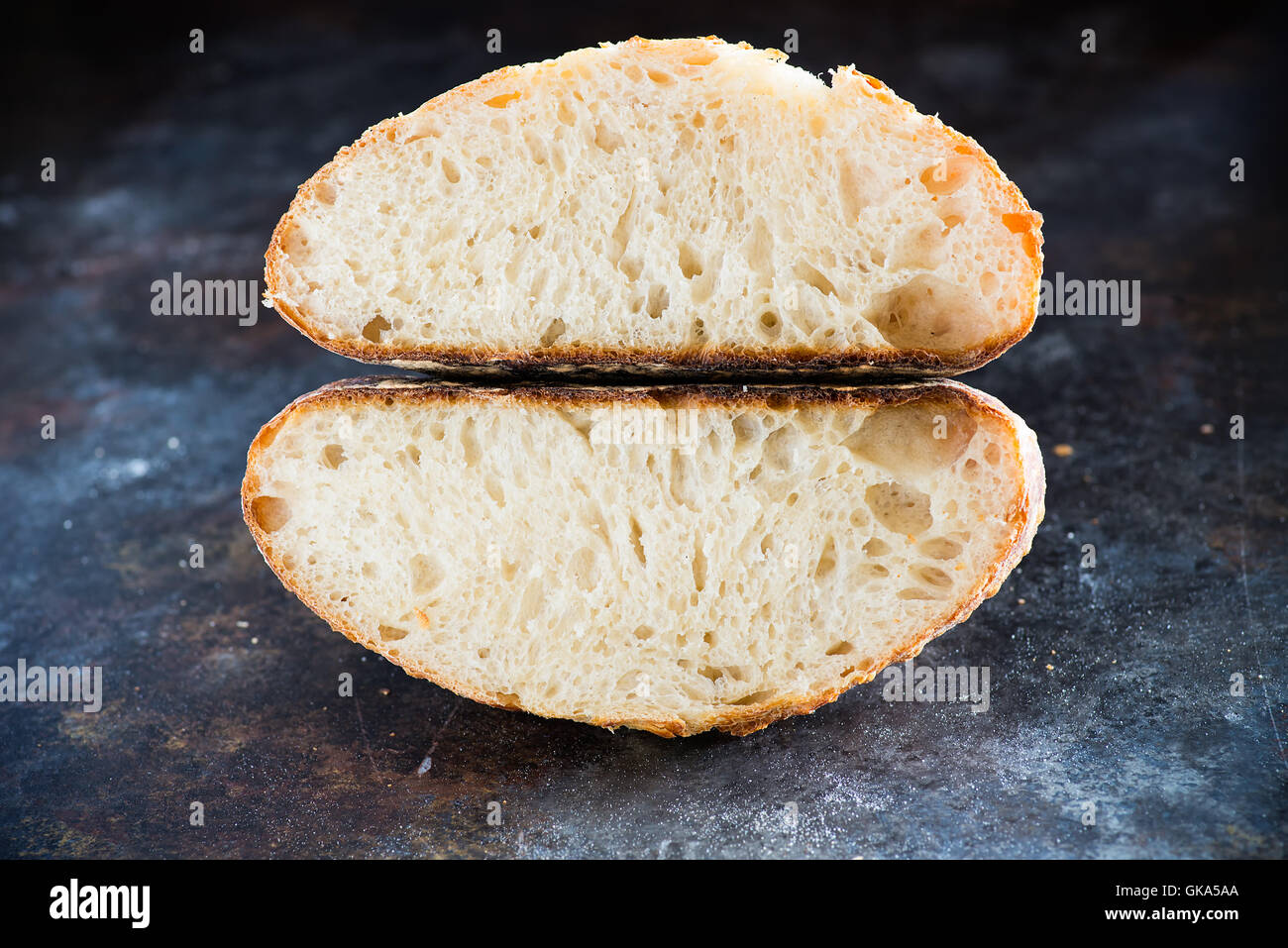 Cortar hogaza de pan de masa fermentada caseras sobre fondo oscuro, closeup Foto de stock