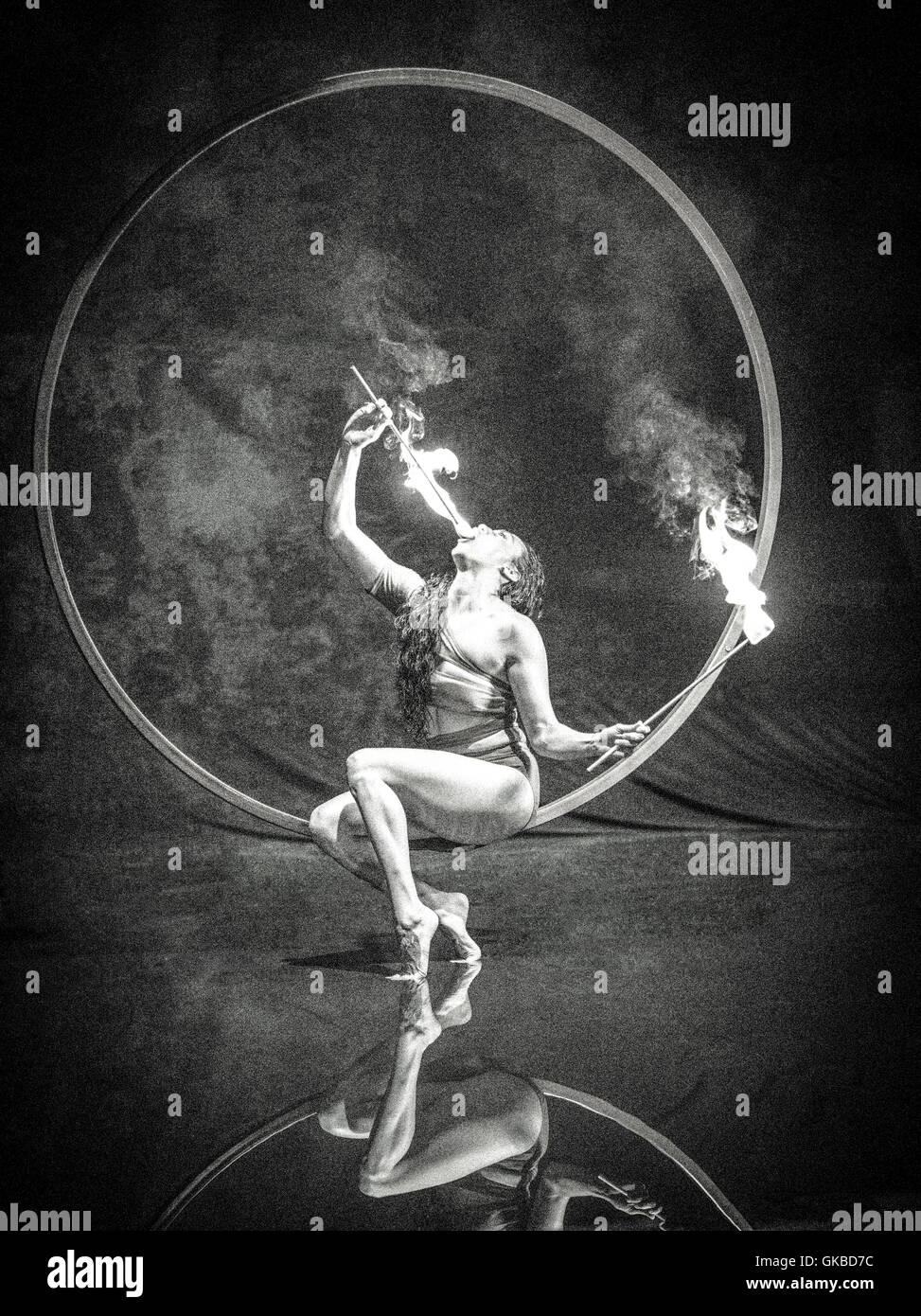 Fire-comiendo una mujer sentada sobre un anillo flotante encima de un grupo de reflexión Foto de stock