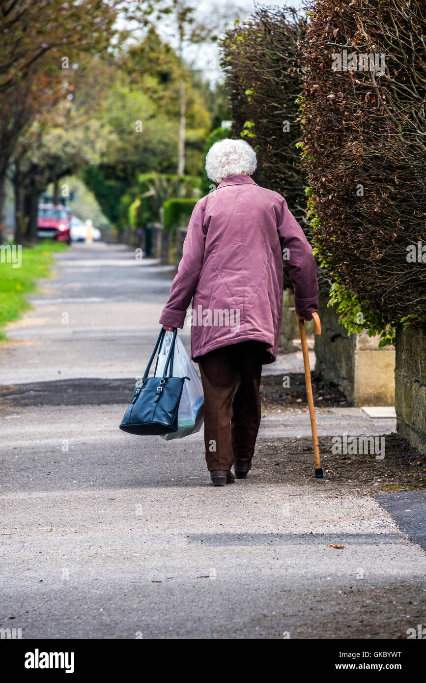 Anciana llevando a casa a pie de tiendas y con bastón Foto de stock